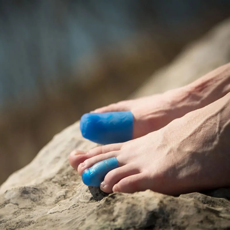 Due piedi con puntali in gel blu su una roccia.