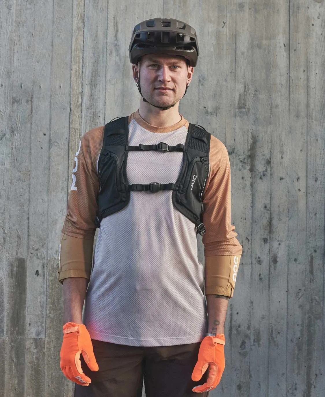 Man with bicycle helmet, orange gloves and Column VPD Backpack. The backpack has two chest straps.