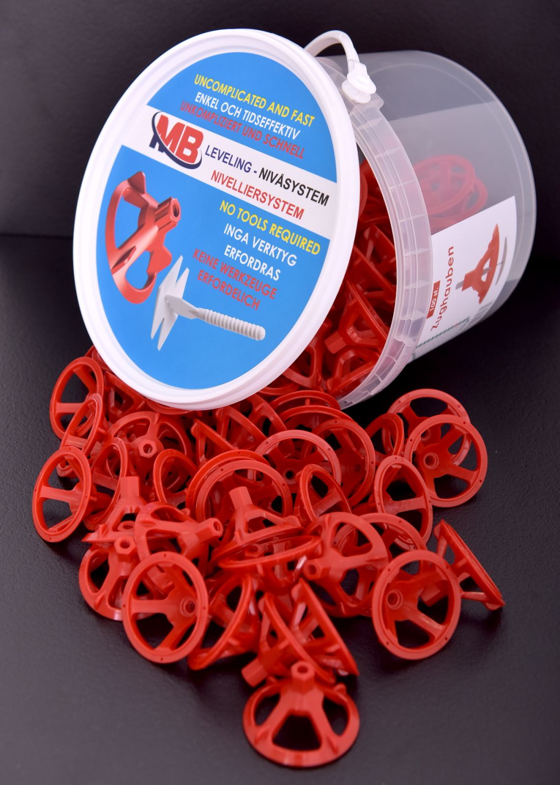 Coiffes de traction MB rouges Un récipient transparent, partiellement rempli de coiffes de traction rouges MB Leveling, basculées sur une surface noire.
