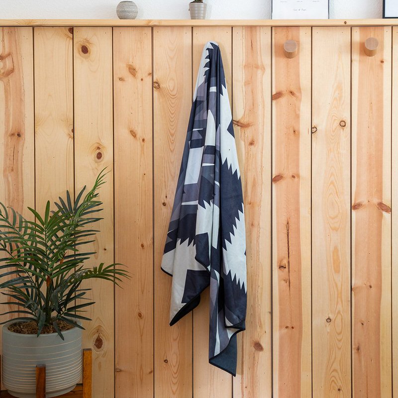 Ein Rumpl Shammy Handtuch mit Woven Daydream Muster hängt an einer Holzwand.