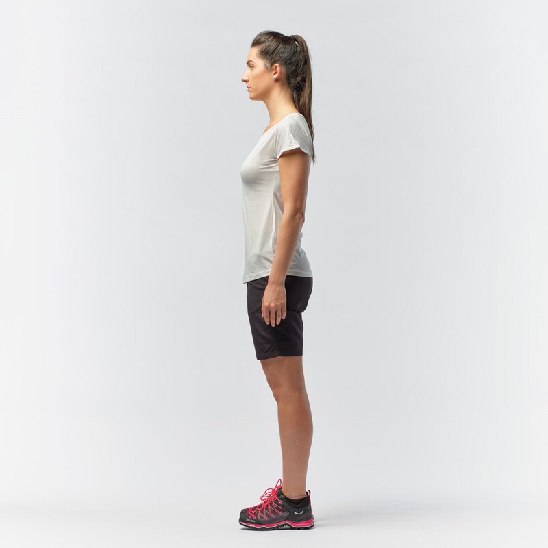 Frau von der Seite, trägt weißes Salewa Puez Melange Dry'Ton T-Shirt, Shorts und Bergschuhe.