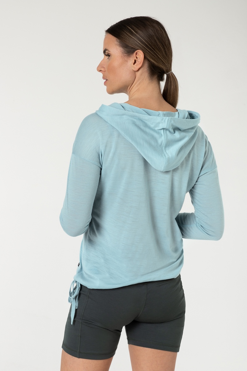 Rückansicht einer Frau mit blauem Kapuzenpullover und grauen Shorts.