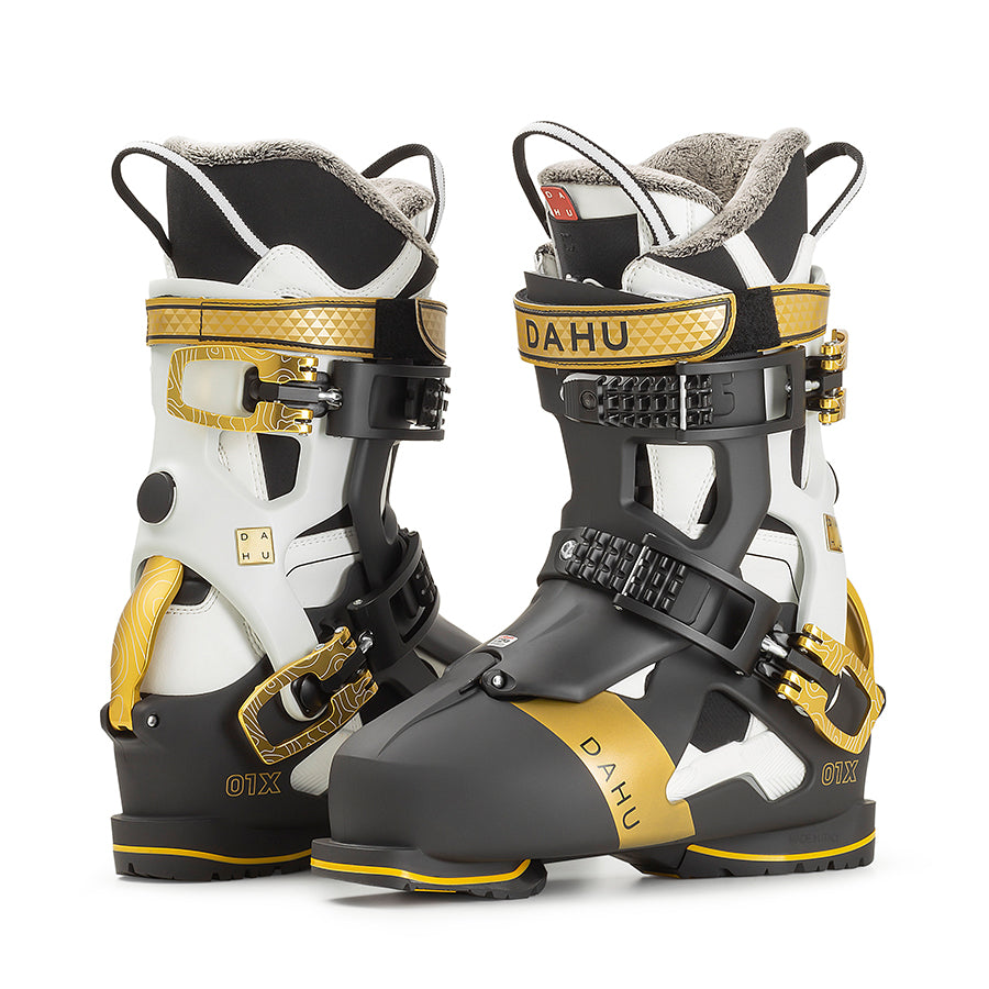 Dahu Ecorce Skischuhe Zwei Dahu Ecorce 01X Skischuhe in Schwarz, Weiß und Gold, seitlich nebeneinander stehend.