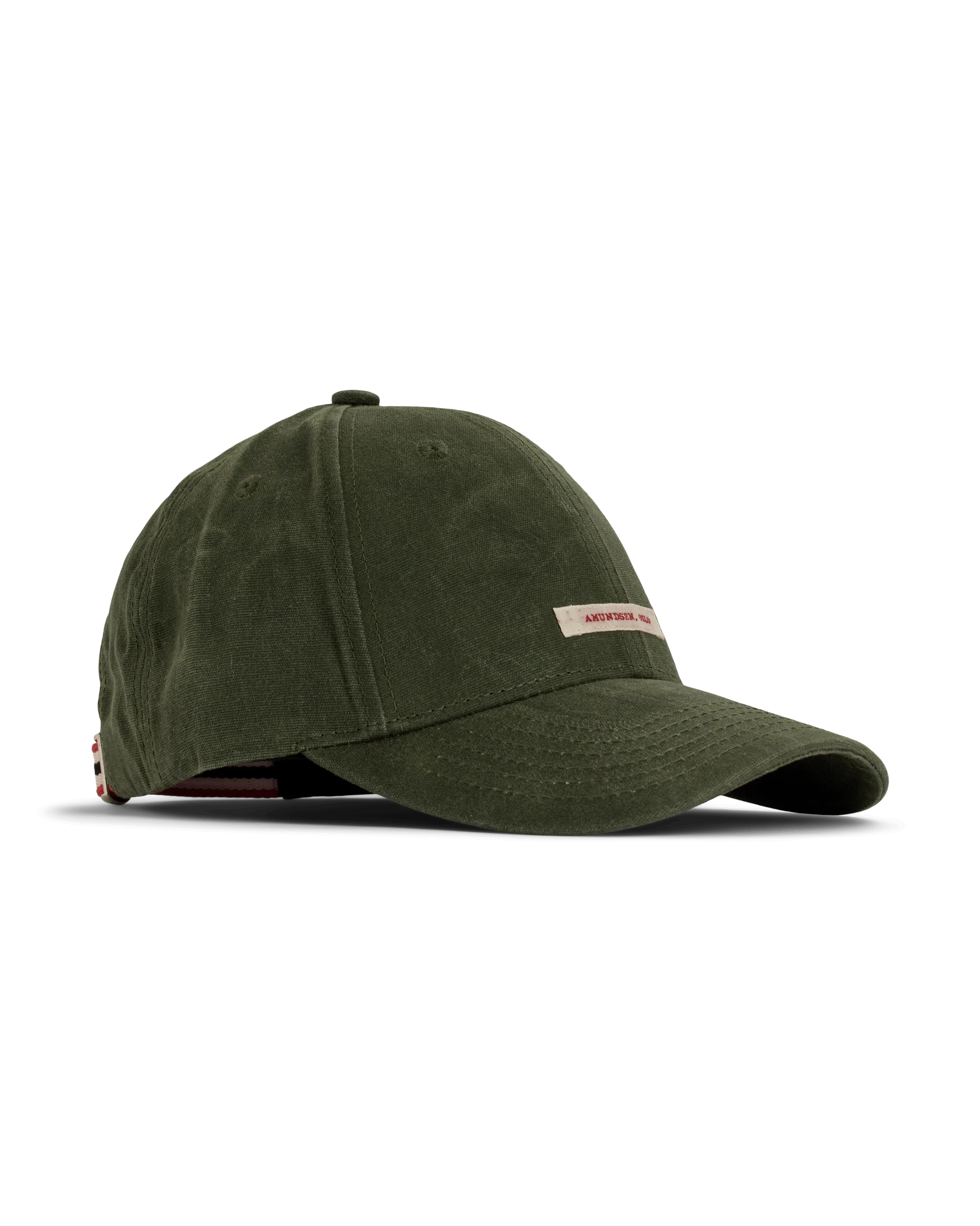 A green baseball cap lies on a white surface. The cap has a small, rectangular label with the words "Amundsen, OSLO" on the front. Red, white, and black stripes are visible on the back.