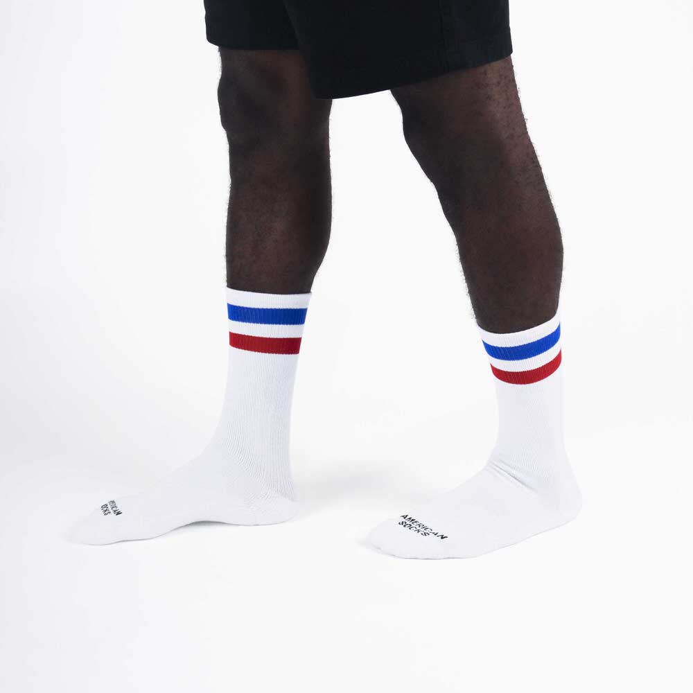 Gestreifte Mid-High Socken Beine mit weißen Mid-High Socken mit blauen und roten Streifen am Bündchen.