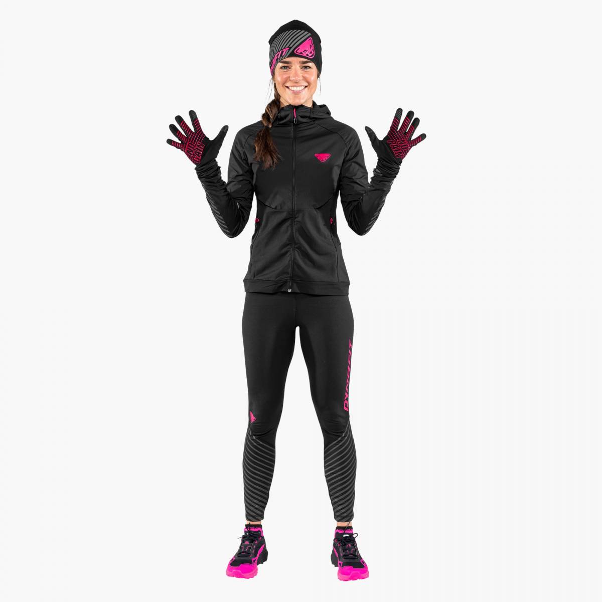 Frau in schwarzer Sportkleidung mit pinkfarbenen Akzenten und reflektierenden Dynafit Alpine Handschuhen.