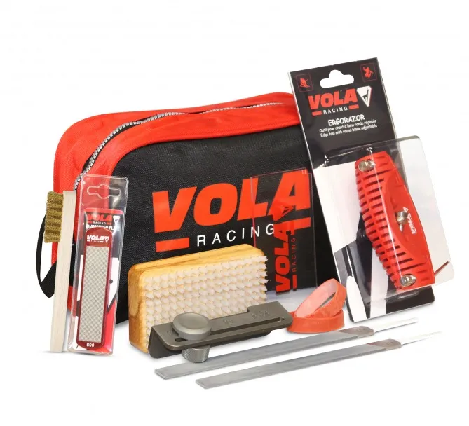 Vola Tuning Kit Plus: strumenti come lima, spazzola, pialla per bordi e pietra abrasiva davanti a una borsa rossa con il logo Vola.
