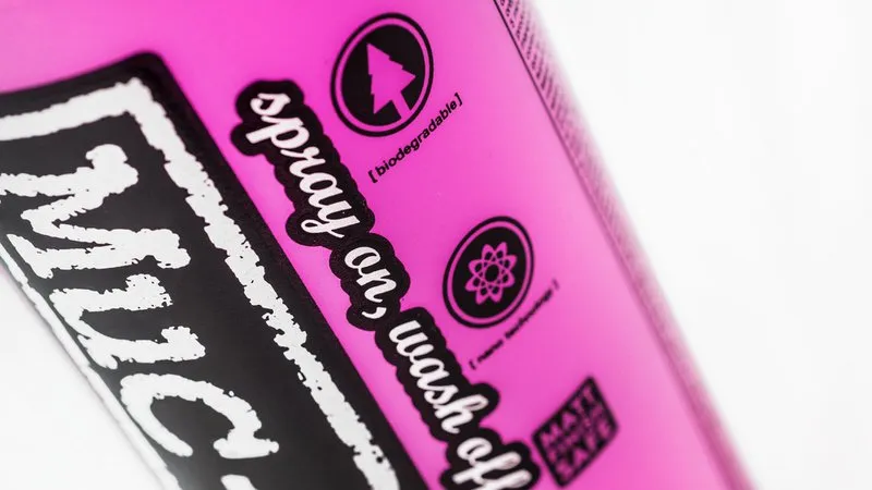 Detailaufnahme einer pinkfarbenen Flasche Muc-Off Fahrradreiniger mit Aufschrift "Spray on, wash off", "biologisch abbaubar" und "Nano-Technologie".