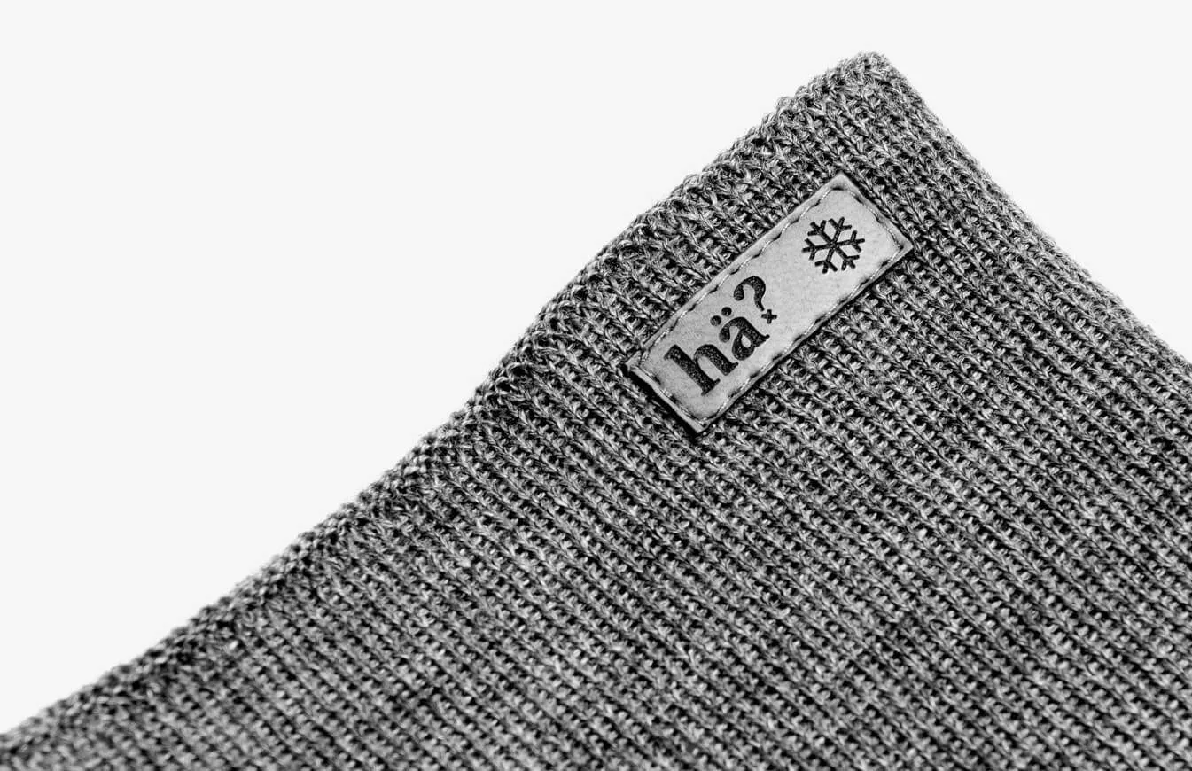 Grauer Merino Neckwarmer im Strickmuster, mit Label "hä?" und Schneeflocke.