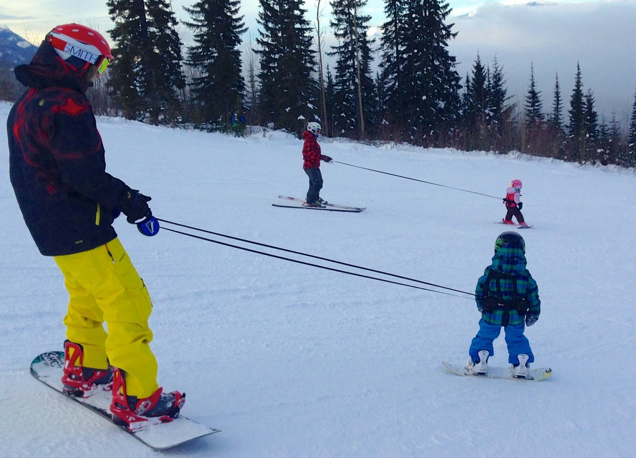 Sur la neige : snowboarder adulte avec Lil' Ripper Gripper Lignes pour aider les enfants à apprendre à skier.