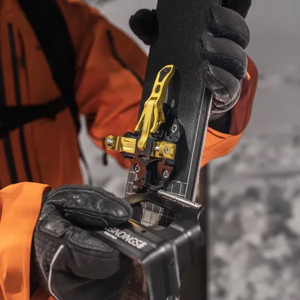 One person mounts ATK crampons on a ski with ATK bindings. The crampons are made of metal.
