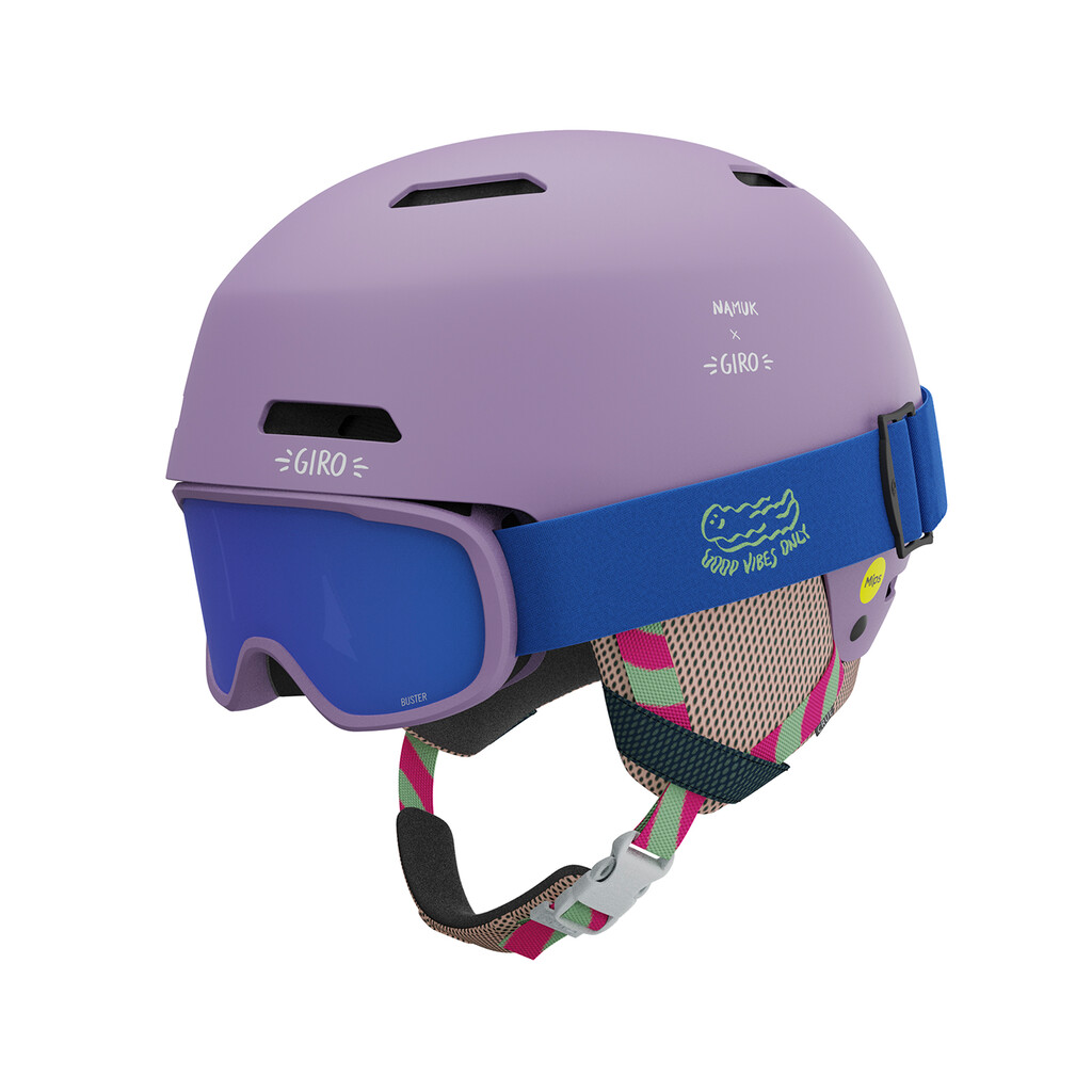 Lavendelfarbener Giro Crüe Mips Skihelm mit blauer Skibrille und gemusterten Riemen.