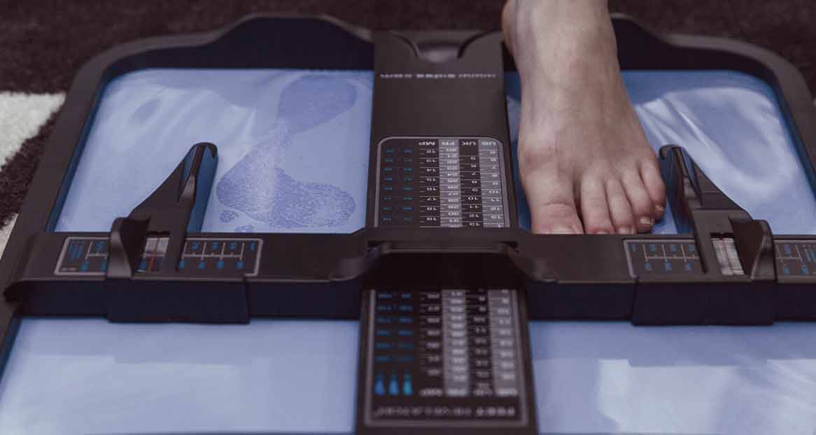 Un pied est mesuré à l'aide d'un appareil de mesure de la pointure ; des empreintes sont visibles sur la surface de mesure.
