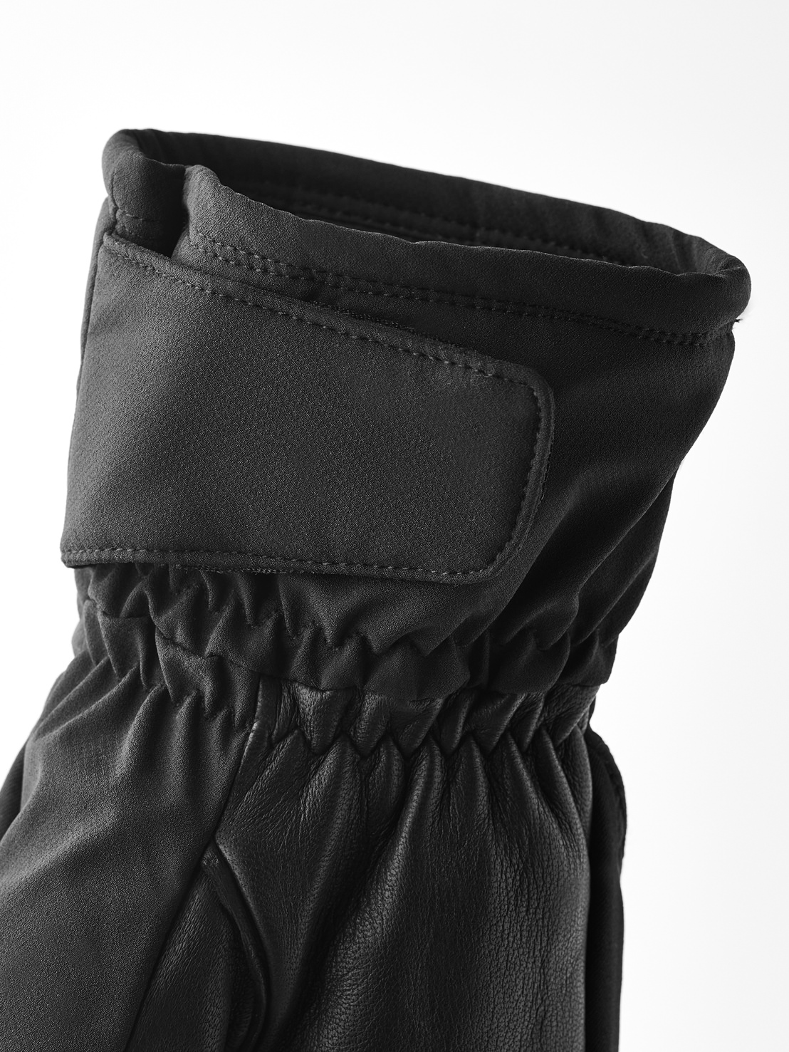 Gros plan sur un gant d'hiver noir, avec une lanière réglable au poignet et une taille élastique.