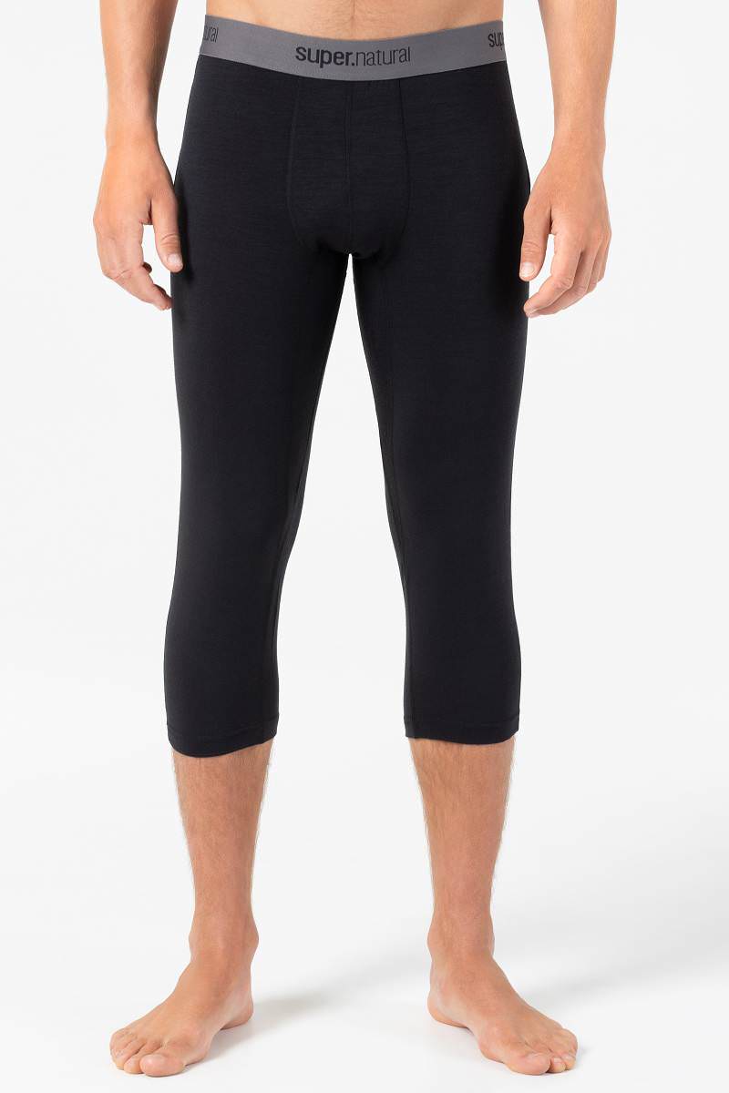 Ein Mann mit schwarzer Super.Natural Base 3/4 Tight 175 Jet Black, stehend auf weißem Hintergrund.