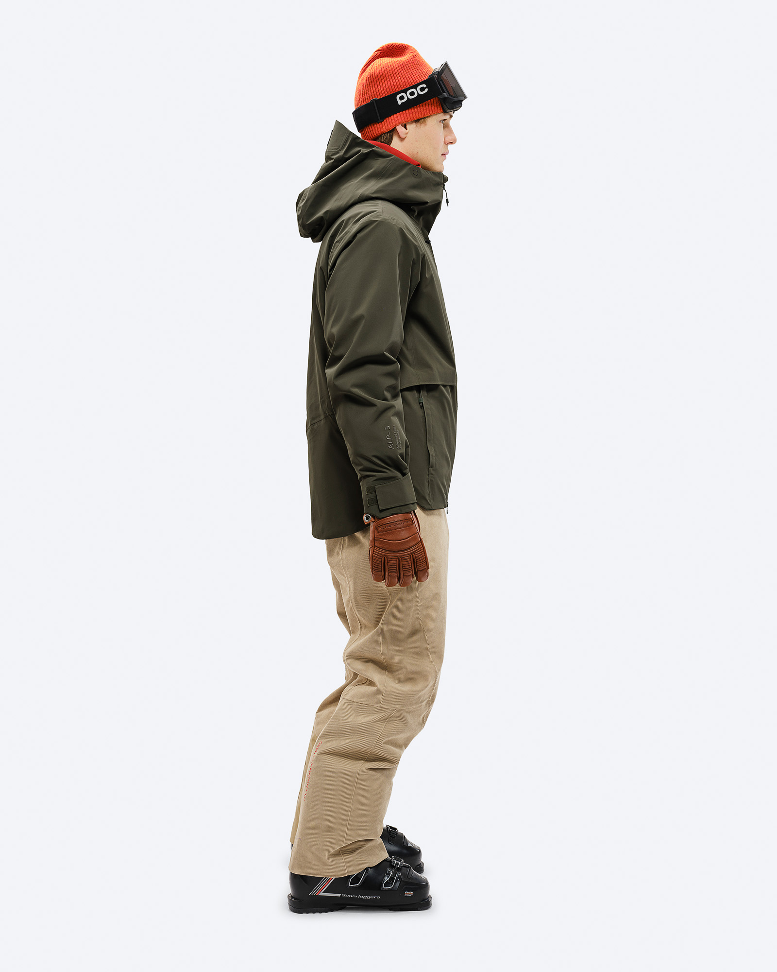 Skieur en veste verte Un homme en vue latérale, portant une veste verte S-3 Carv Insulated Stretch Jacket, un pantalon de ski, un bonnet et des lunettes de ski.