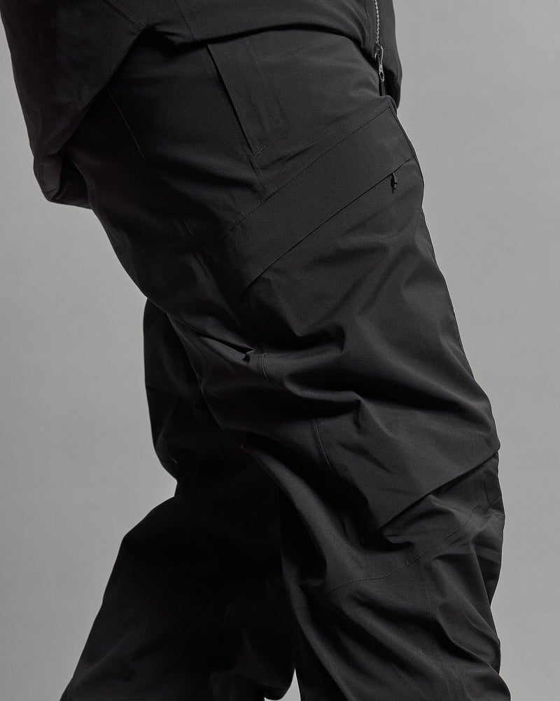Pantalon stretch GORE-TEX Détail d'un pantalon GORE-TEX Stretch noir isolé avec poche sur la jambe et pli au genou.
