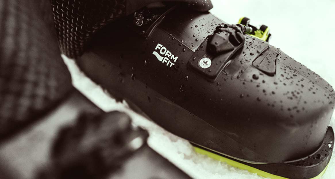 Dripping ski boot Close-up of a dark, dripping ski boot with a yellow edge on snow. The inscription "FORM FIT" can be seen.