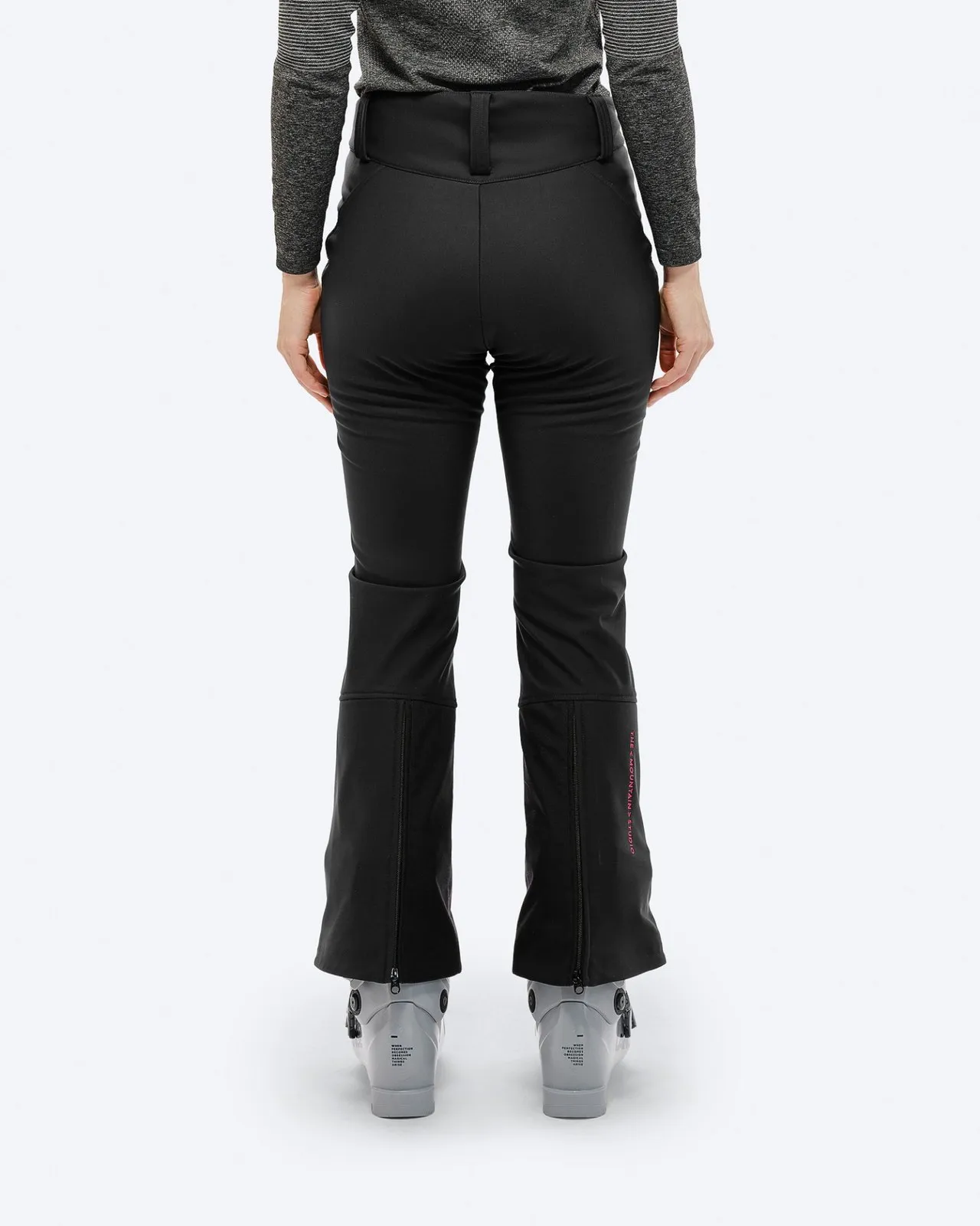 Rückansicht: Schwarze P-4 W 2L Stretch Ski Pants mit Skischuhen und pinkem Logo am Beinabschluss.