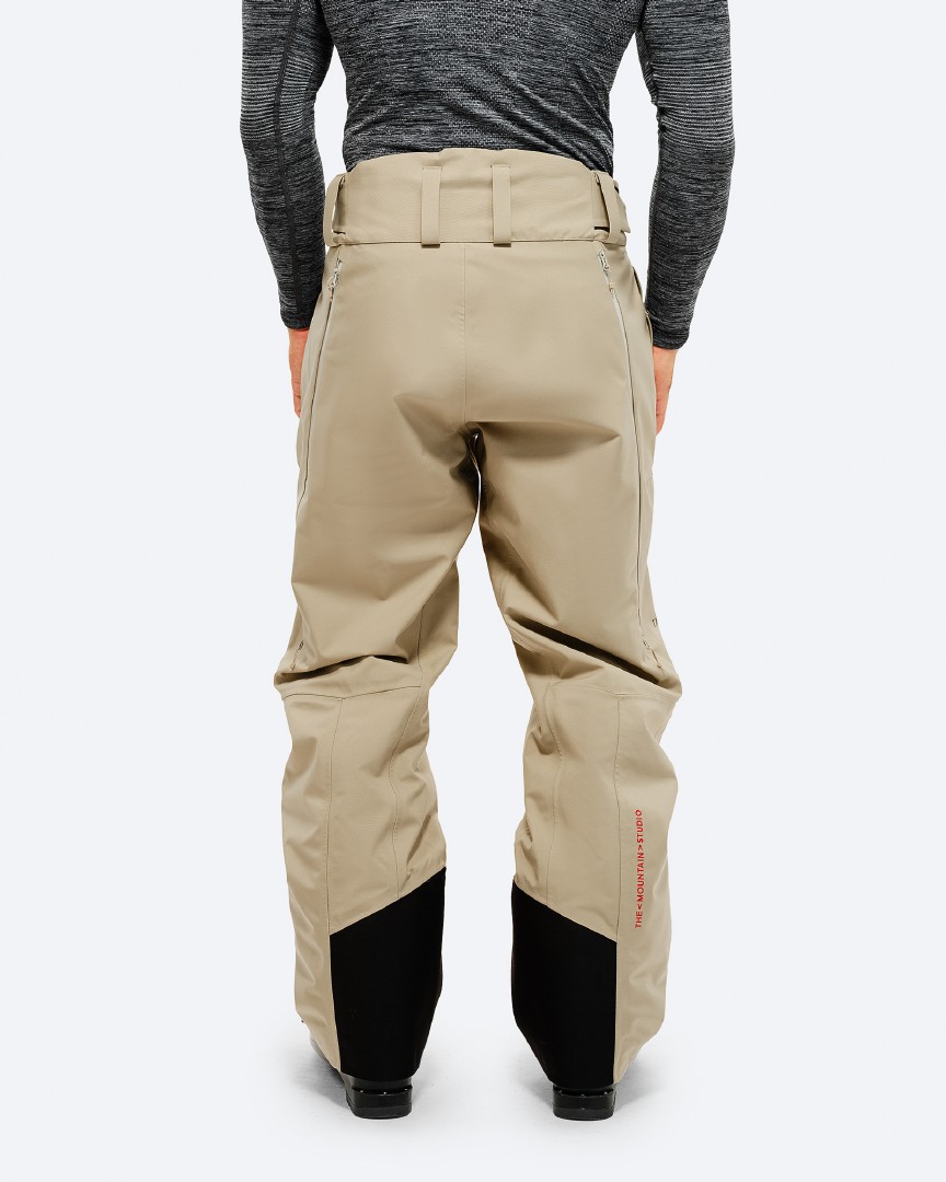 Rückansicht P-7 Ride Hose Rückansicht der "P-7 Ride Insulated Pant Seneca Rock" in Beige mit schwarzen Verstärkungen am Beinende.