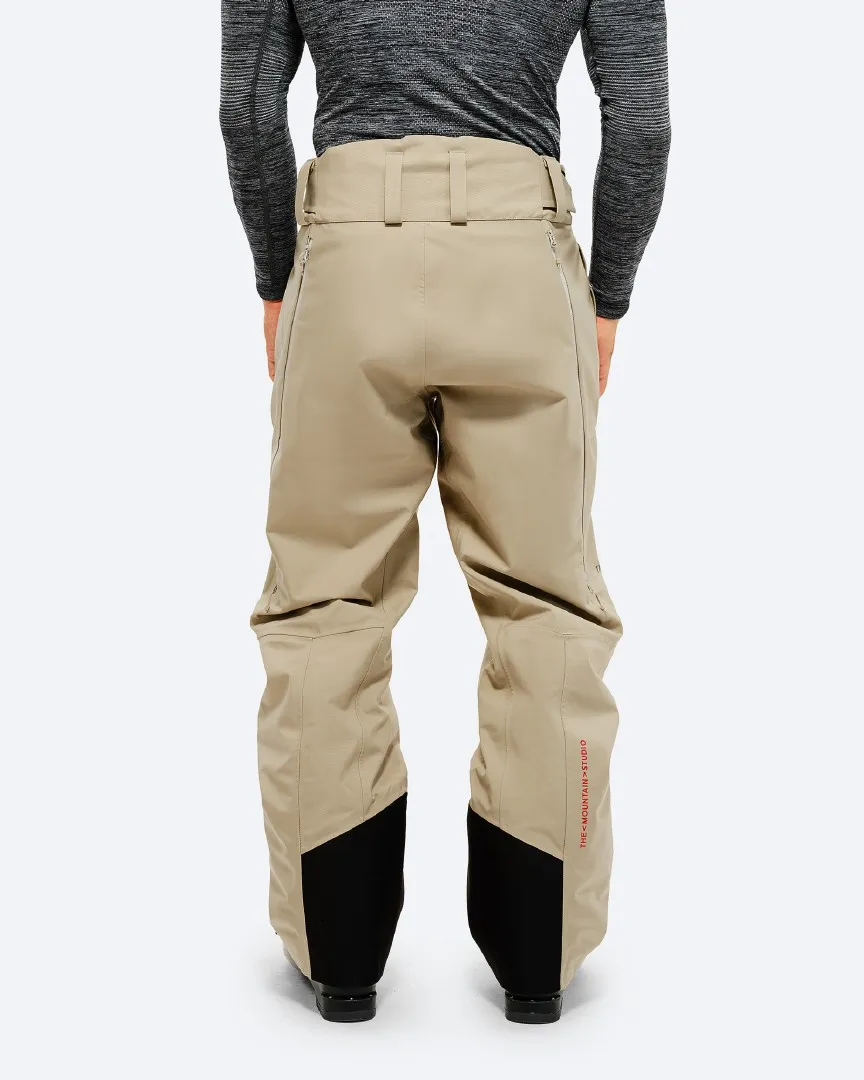 Rear view of the "P-7 Ride Insulated Pant Seneca Rock" in beige with black reinforcements at the leg ends.