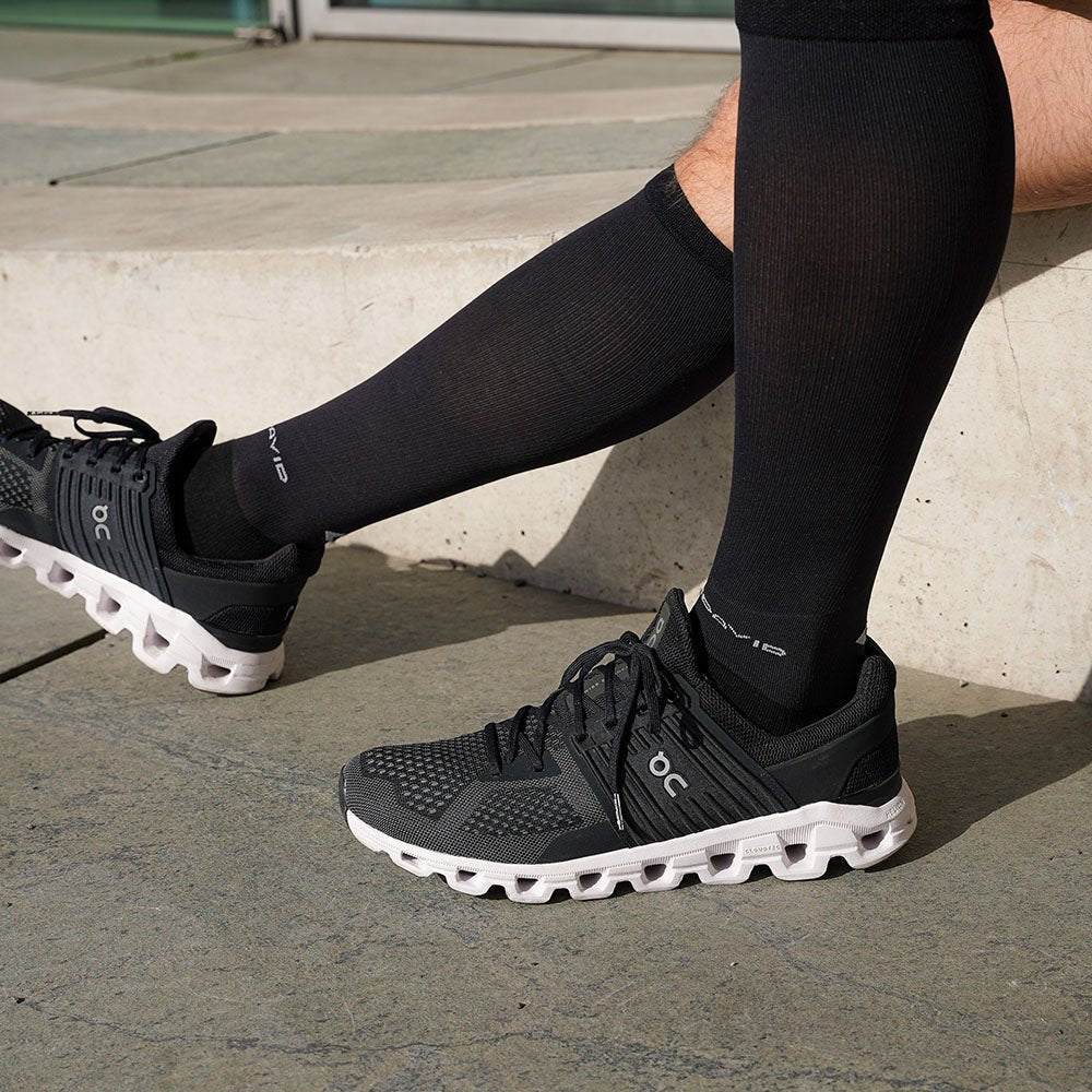 Compression socks and sneakers Legs with black MCDavid compression socks and sneakers on a stone staircase.