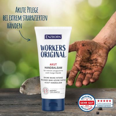 Tube de baume pour les mains "Workers Original" à côté d'une main sale sur fond vert sur un bois avec une pelle.