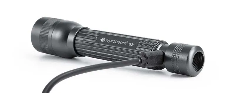 Dunkelgraue Suprabeam Q2r LED-Taschenlampe, liegend, mit Micro-USB Kabel zum Aufladen verbunden.
