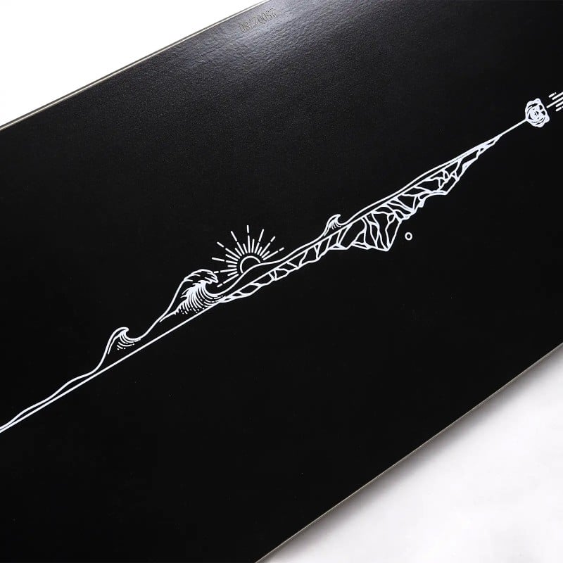 Jones Flagship Pro Detail Detailaufnahme des Jones Flagship Pro Snowboards: Schwarze Oberfläche mit weißer Grafik aus Sonne, Welle und Berglandschaft.