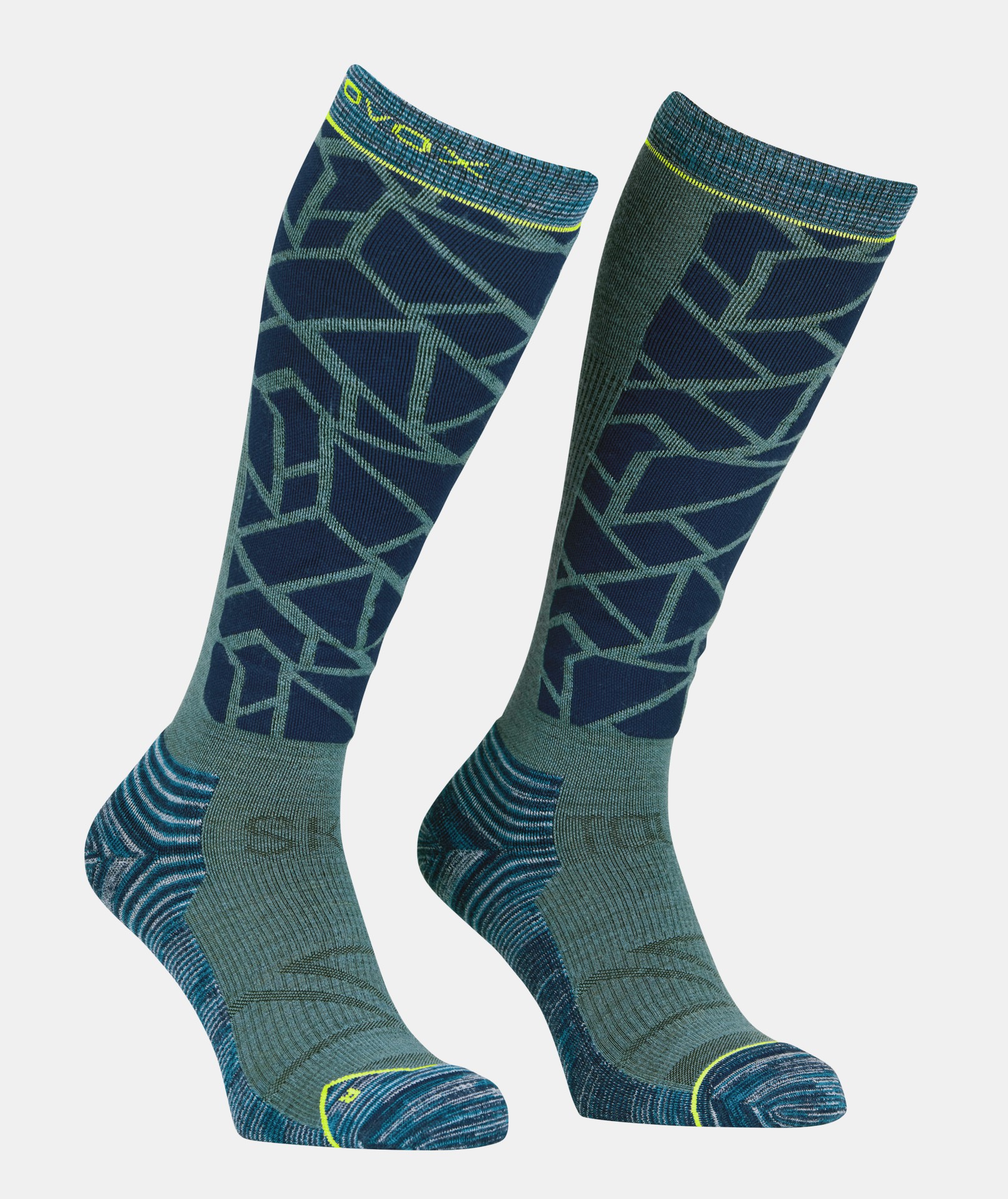 Chaussettes de ski de randonnée bleues Deux bas de compression bleus Ski Tour au motif géométrique se tiennent debout sur un fond neutre.