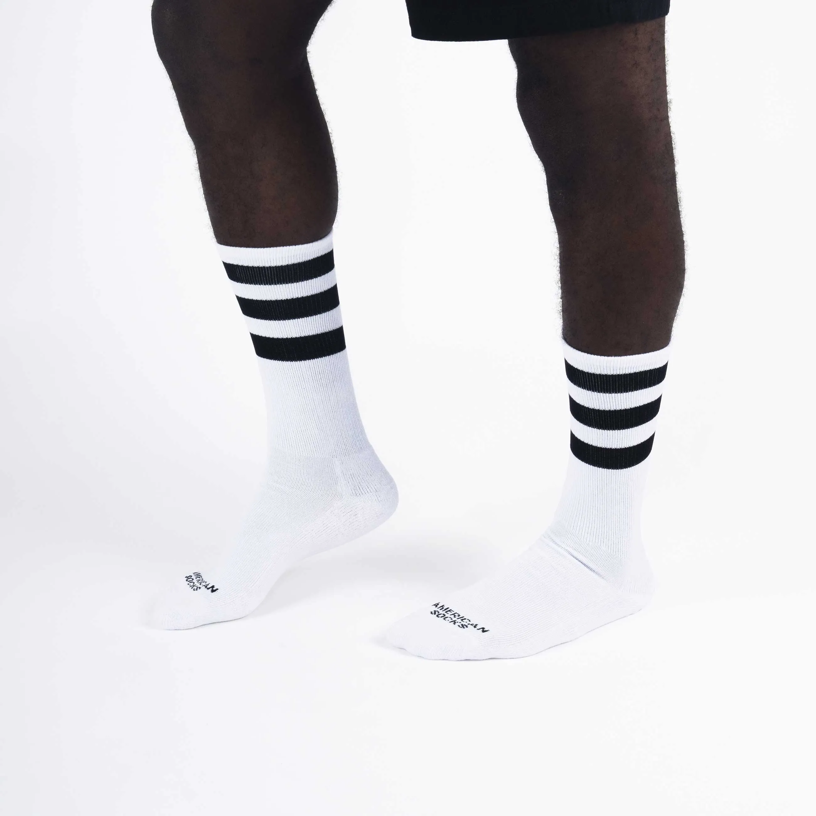 Legs with white, knee-high socks. Each sock has three black stripes on the leg.