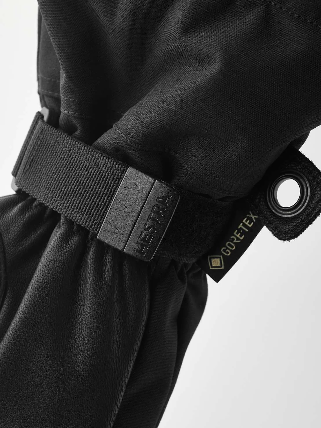 Close-up of a black Hestra Army Leather Gore-Tex mitten with strap and Gore-Tex label.