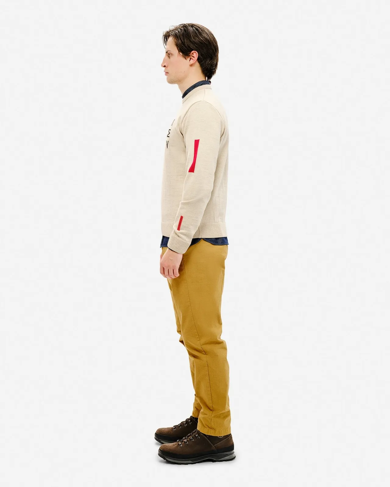Uomo di profilo con maglione da sci St. Moritz, maglione beige con dettagli rossi e pantaloni gialli.