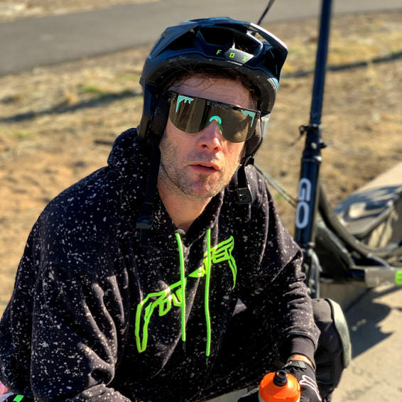 Mann mit Sonnenbrille Mann mit Helm und Thundermint Elliptical Sonnenbrille, Kapuzenpulli, ElliptiGO im Hintergrund.