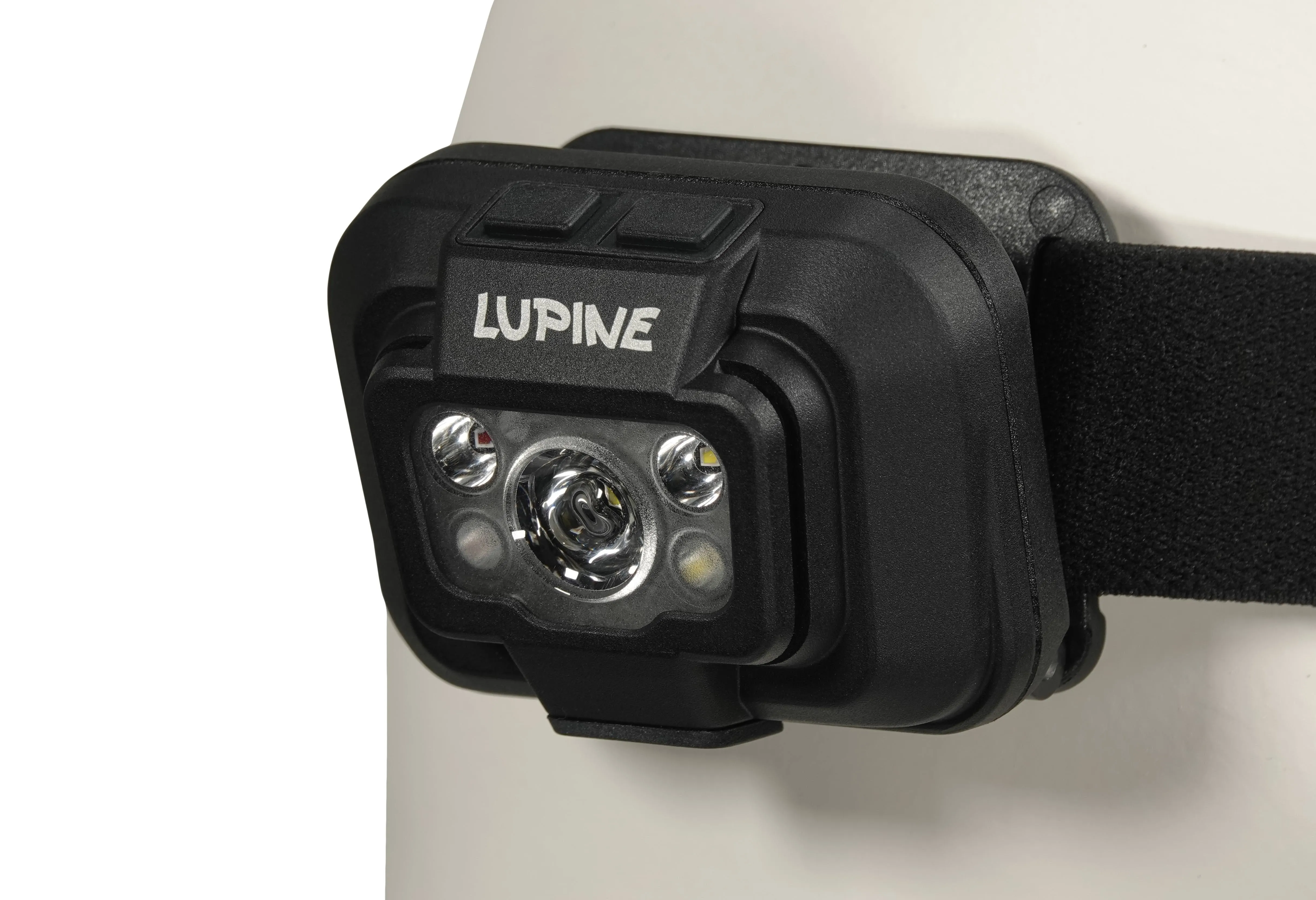 Vue détaillée de la lampe frontale Penta avec le logo Lupine, deux boutons et des lampes LED. Le bandeau noir est fixé.