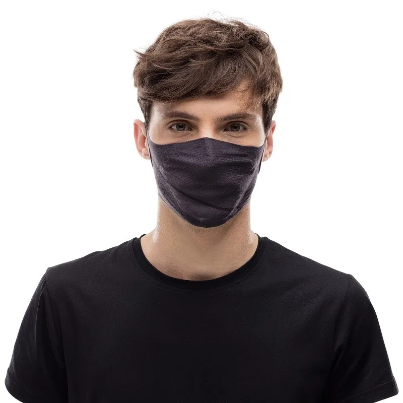 Portrait d'un homme portant un masque en tissu gris. Le masque couvre le nez et la bouche. Il porte un t-shirt noir.