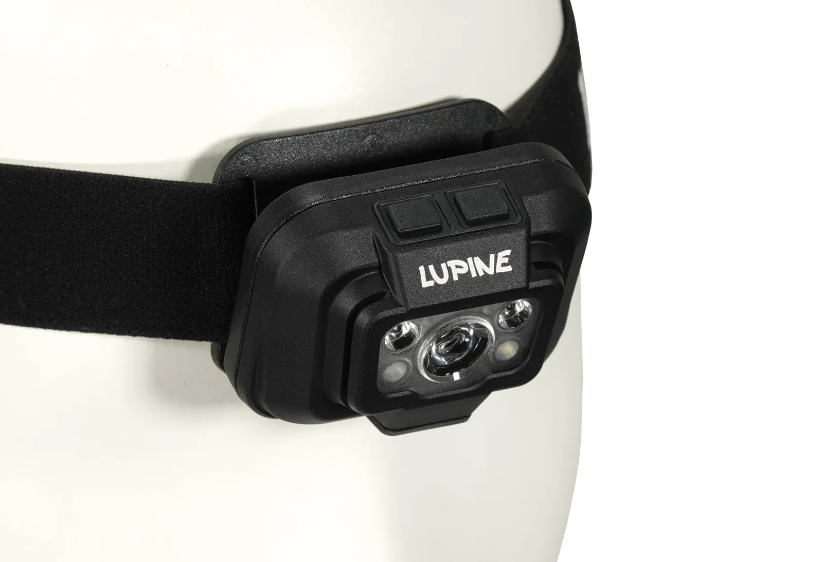 Gros plan d'une lampe frontale Penta avec un bandeau noir sur une tête blanche. Inscription "Lupine".