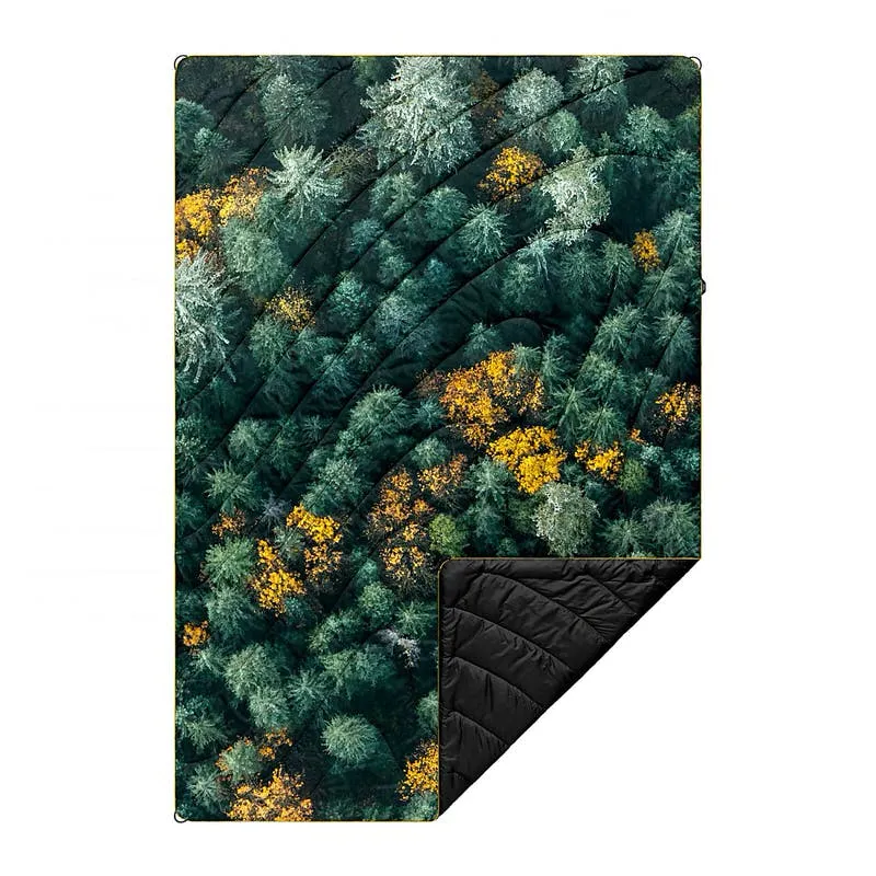 Puffy Blanket mit Waldmuster; grüne, goldene und weiße Baumkronen von oben. Eine Ecke ist umgeschlagen und zeigt schwarzes Futter.