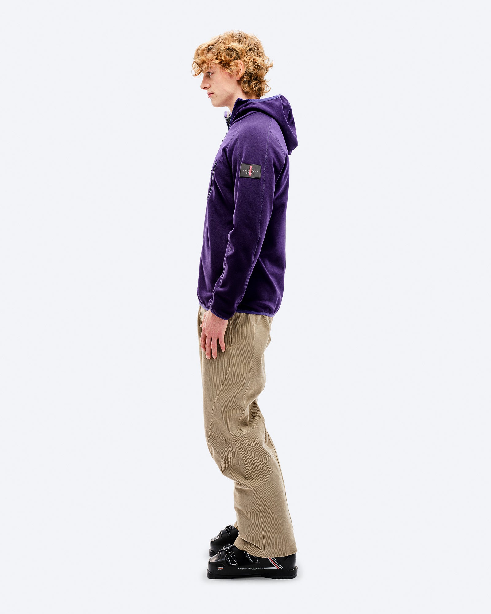 Tenue M-7 Fleece L'homme porte une capuche M-7 Tech Fleece Parachute Purple, un pantalon beige et des chaussures noires de profil.