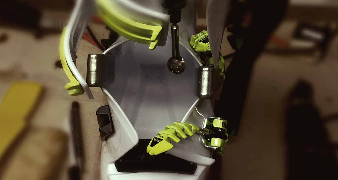 Une chaussure de ski est usinée à l'aide d'une fraise afin de l'adapter au pied. Les parties métalliques et les détails jaunes sont visibles.