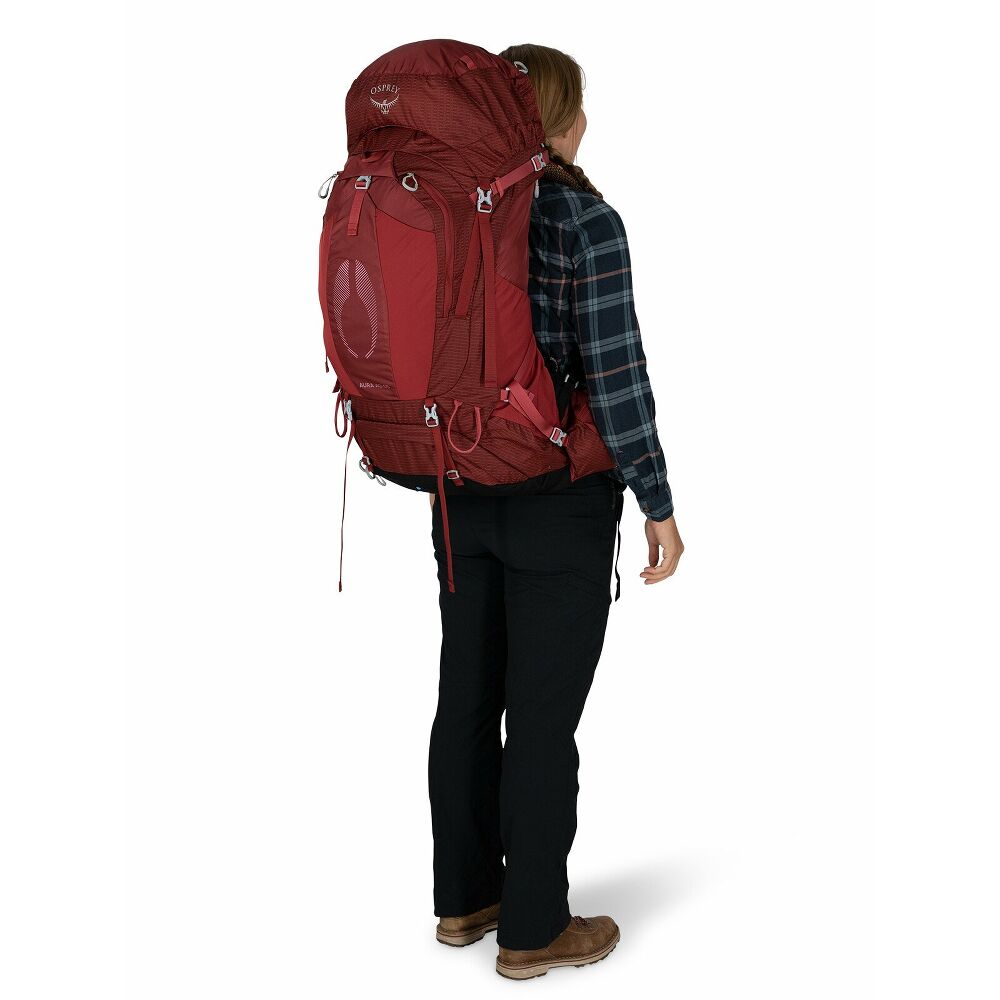 Rückansicht einer Frau mit rotem Osprey Aura AG 65 Damen-Trekkingrucksack. Sichtbar ist das AntiGravity Rückensystem mit gespanntem 3D-Mesh für ergonomische Passform und Komfort auf langen Touren. Gurte und Taschen.