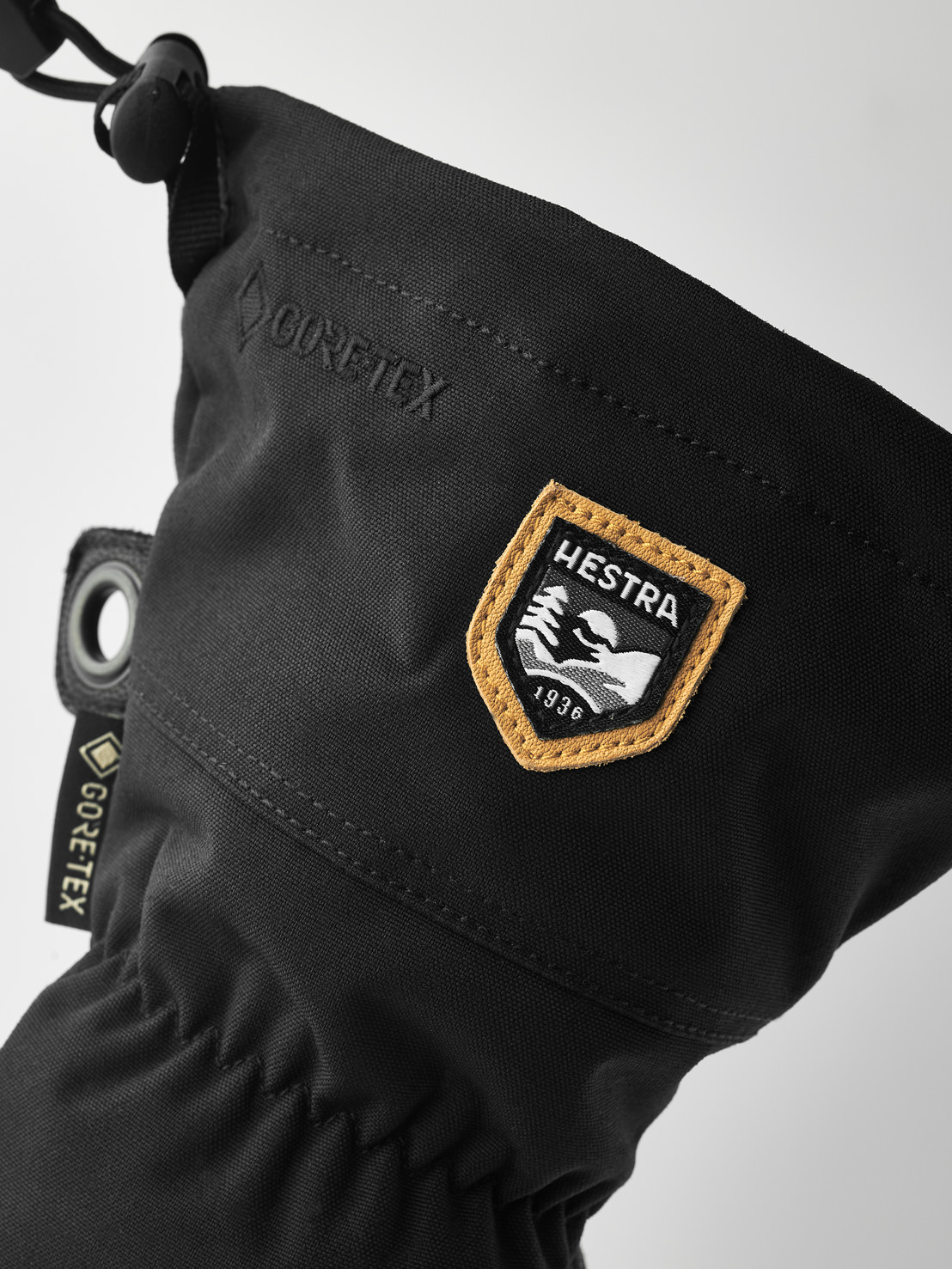 Hestra Moufles en cuir Army Vue détaillée d'une moufle noire Hestra Army Leather Gore-Tex avec logos et cordon de serrage.