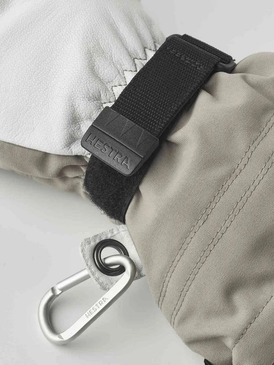 Nahaufnahme eines Hestra Army Leather Heli Ski Mitt mit Karabinerhaken und Klettverschluss am Handgelenk.