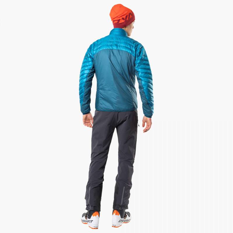 Rückansicht eines Mannes mit Dynafit TLT Touring DST Hose, blauer Jacke und Mütze.
