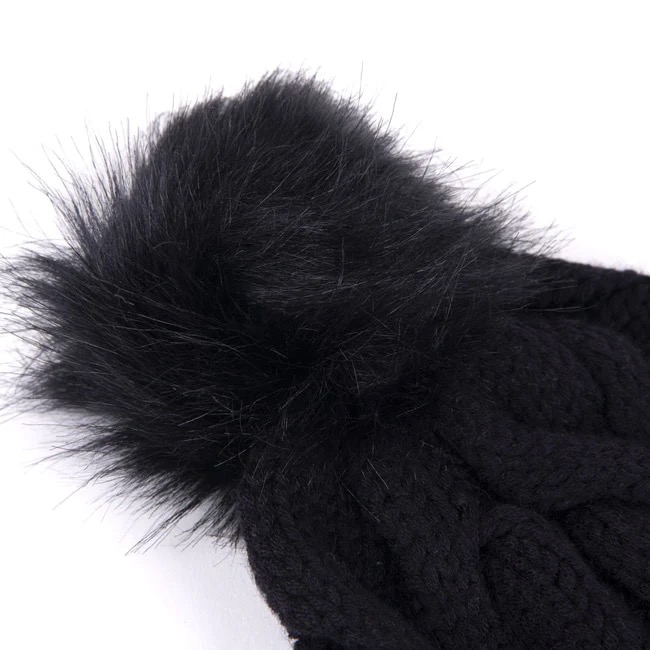 Gros plan sur un bonnet tricoté noir avec un grand pompon en fourrure synthétique duveteuse.