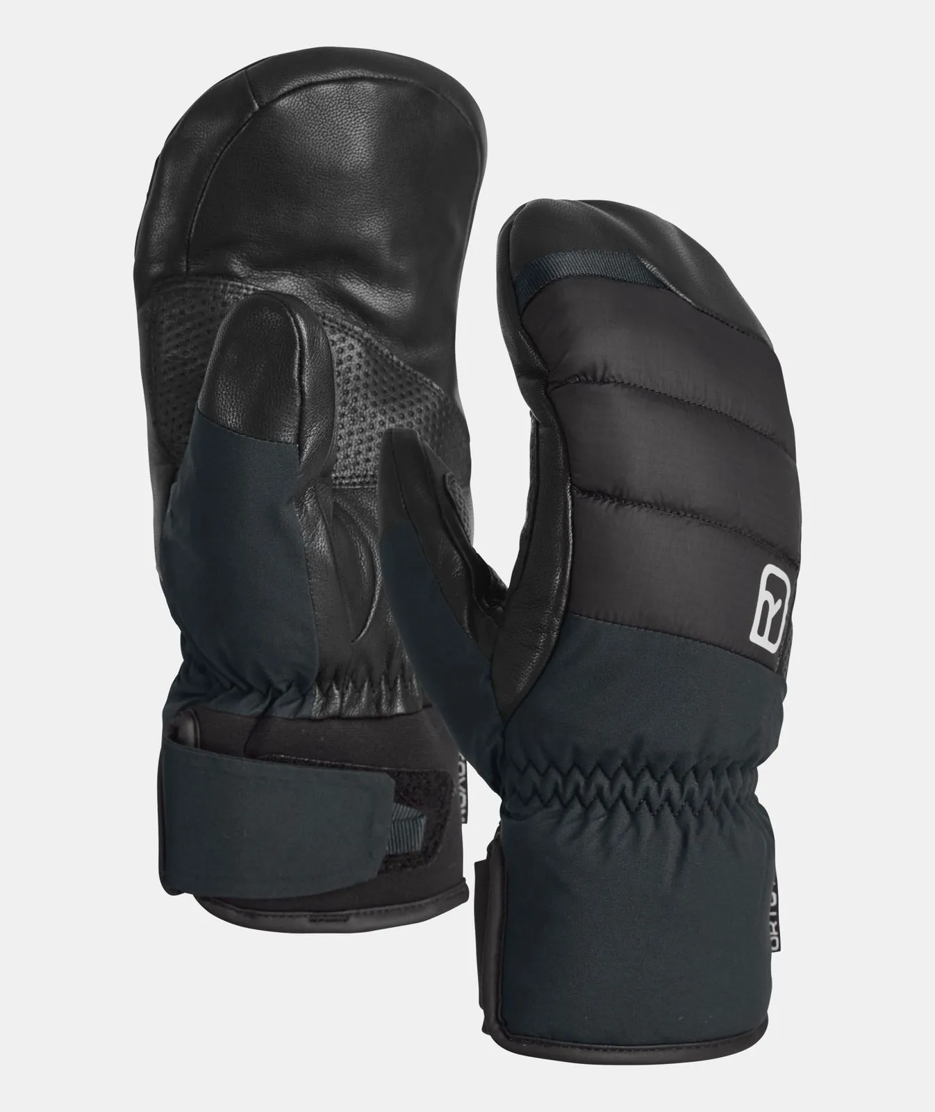 Two black Ortovox Freeride Cozy Mitten mittens against a neutral background. Leather details and quilted seams.