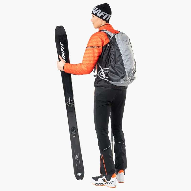 Person mit Dynafit Ausrüstung hält Blacklight 95 Ski. Touren-Setup mit Rucksack und passender Bekleidung.