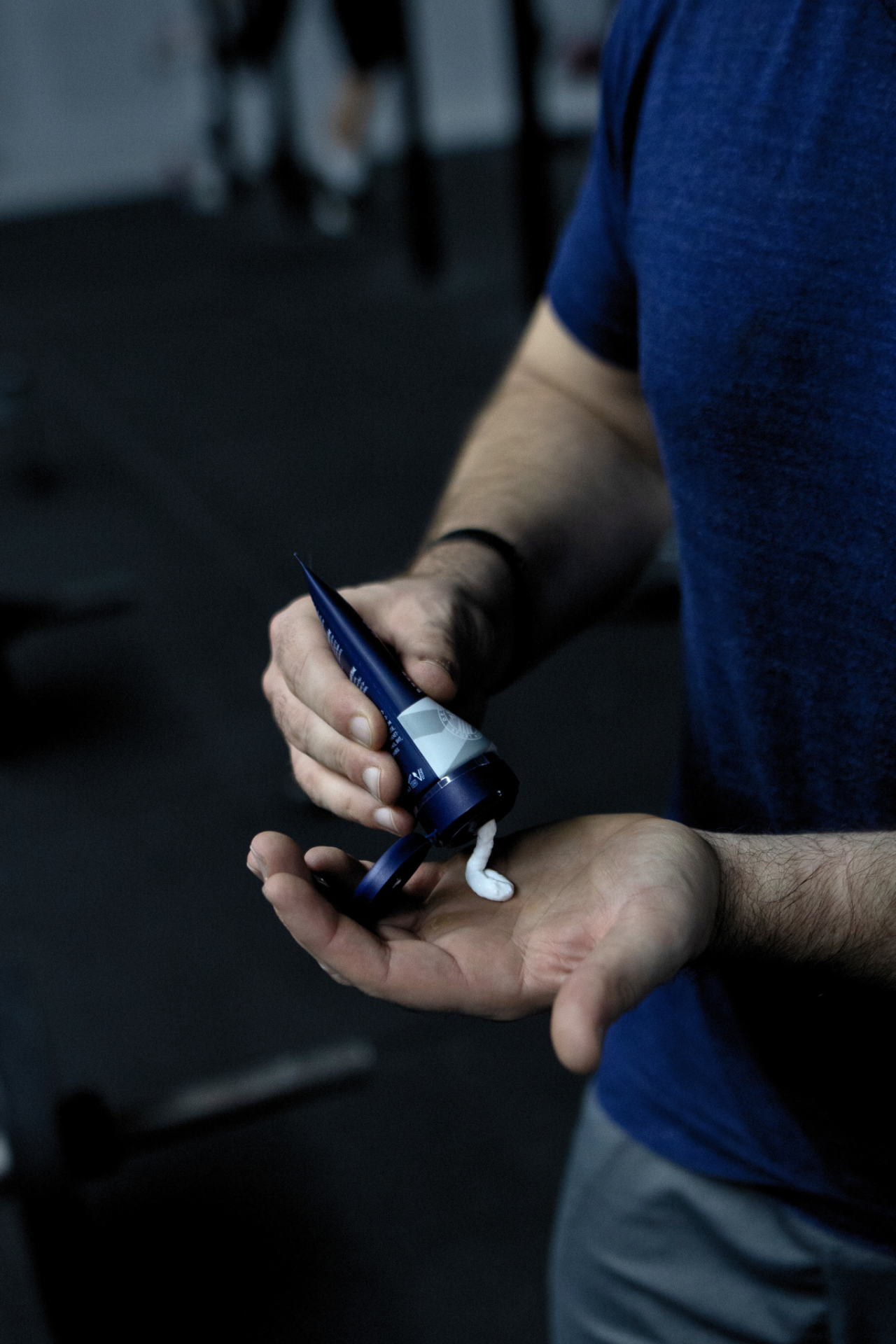 Mann drückt SPORT LAVIT Super Grip in die Hand. Tube blau-weiß mit weißer Creme.