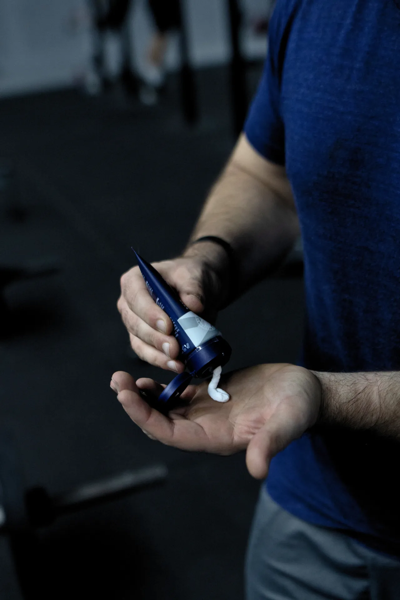 Mann drückt SPORT LAVIT Super Grip in die Hand. Tube blau-weiß mit weißer Creme.
