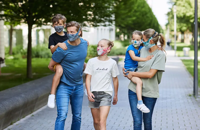 Famille avec masques filtrants en bleu et blanc sur un trottoir. Les masques filtrants Buff sont confortablement installés.
